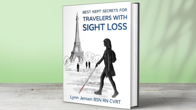Lynn Jensen's book, 'Best Kept Secrets for Travelers With Sight Loss' sitting on a shelf in front of a pale green wall.  On the cover, a silhouette of a female traveler is shown in profile, walking with a white mobility cane in her right hand. The traveler is in full stride with her right foot forward and the marshmallow cane tip extended to the far left. She is wearing a short open trench coat, leggings, a small backpack, and walking shoes. In the background is the Eiffel Tower with three tourists and a few trees.